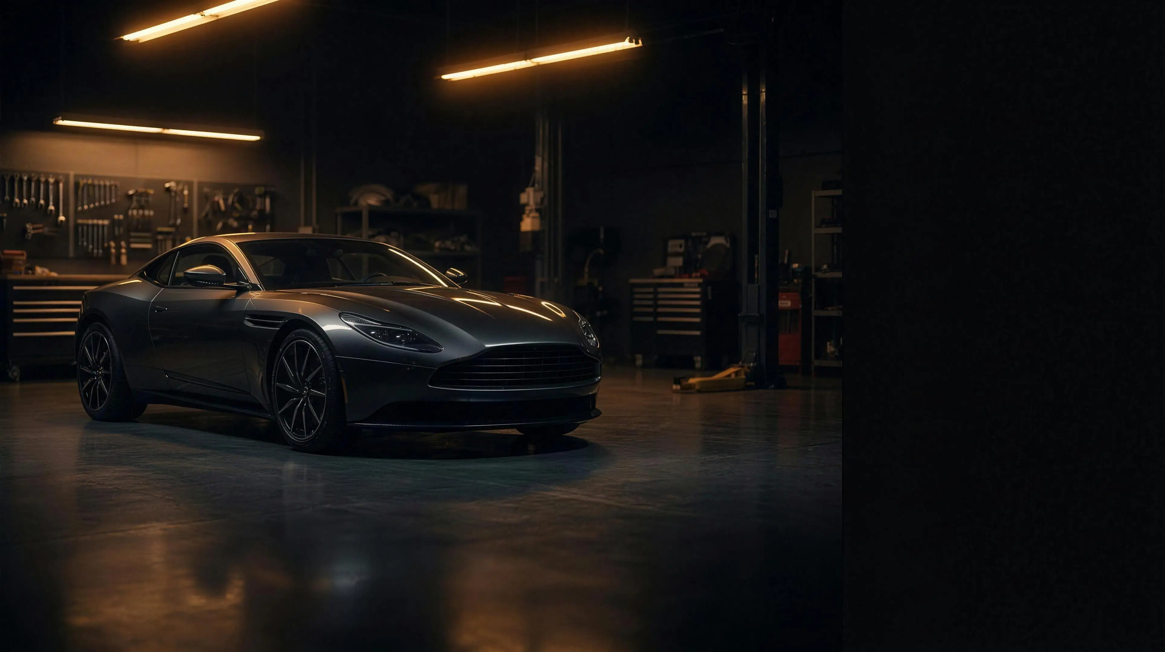 The coupe in a dark shop bay, lit by amber striplights
